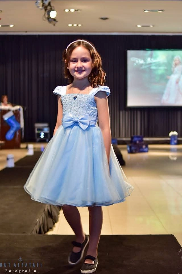 Niña con vestido celeste de fiesta sobre pasarela