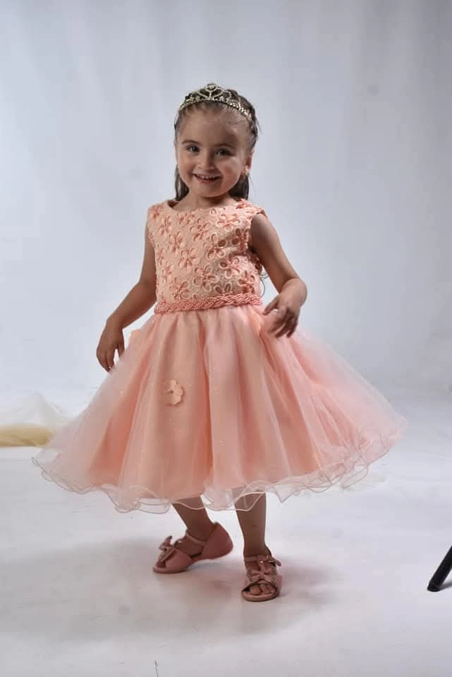 Niña con vestido durazno de fiesta en estudio
